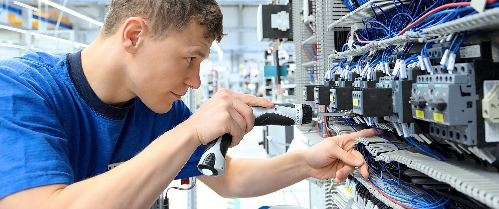 young operator assembles machine in a modern high tech factory - production of switch cabinets for industrial plant