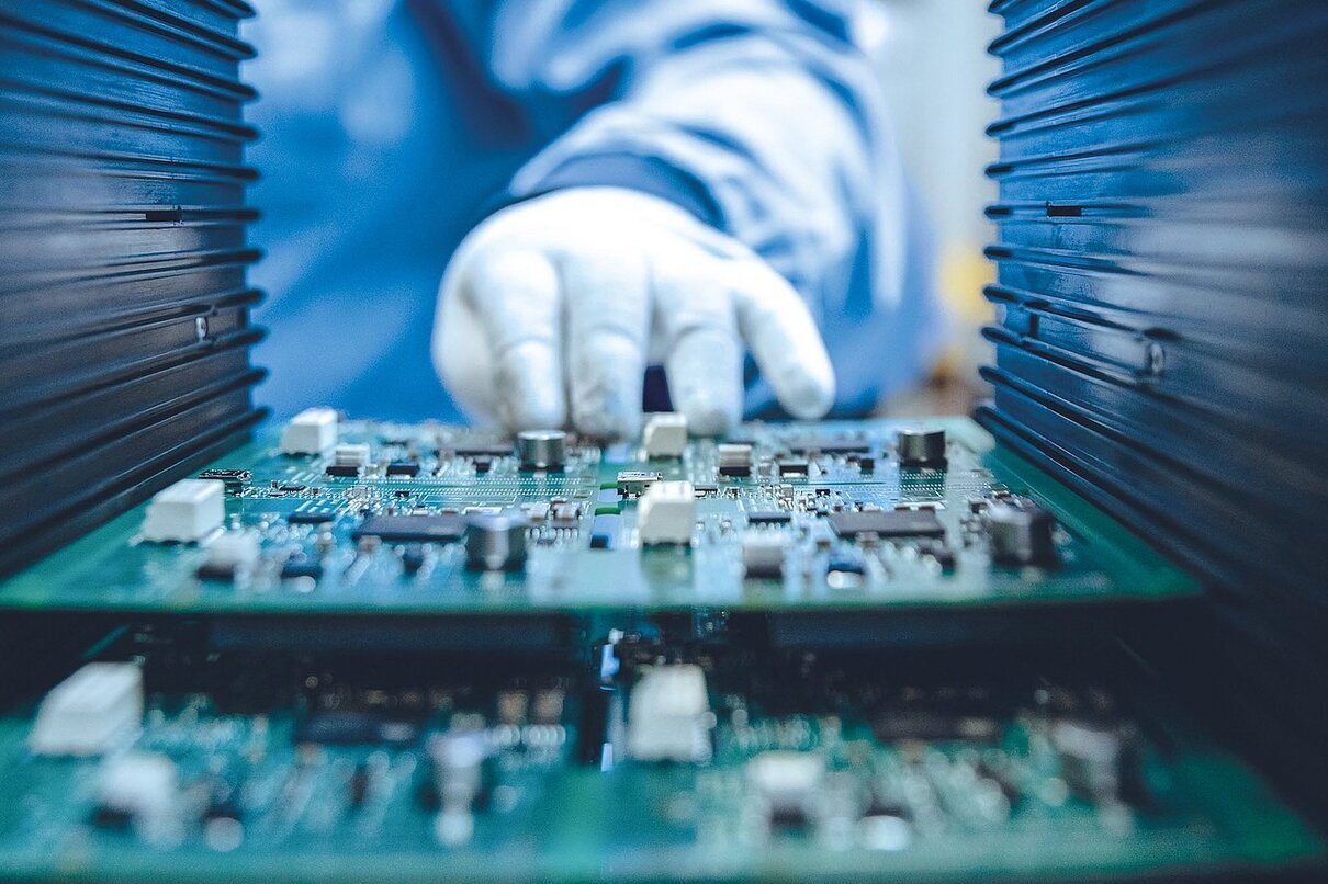 Young Female Blue and White Work Coat is Using Plier to Assemble Printed Circuit Board for Smartphone. Electronics Factory Workers in a High Tech Factory Facility.