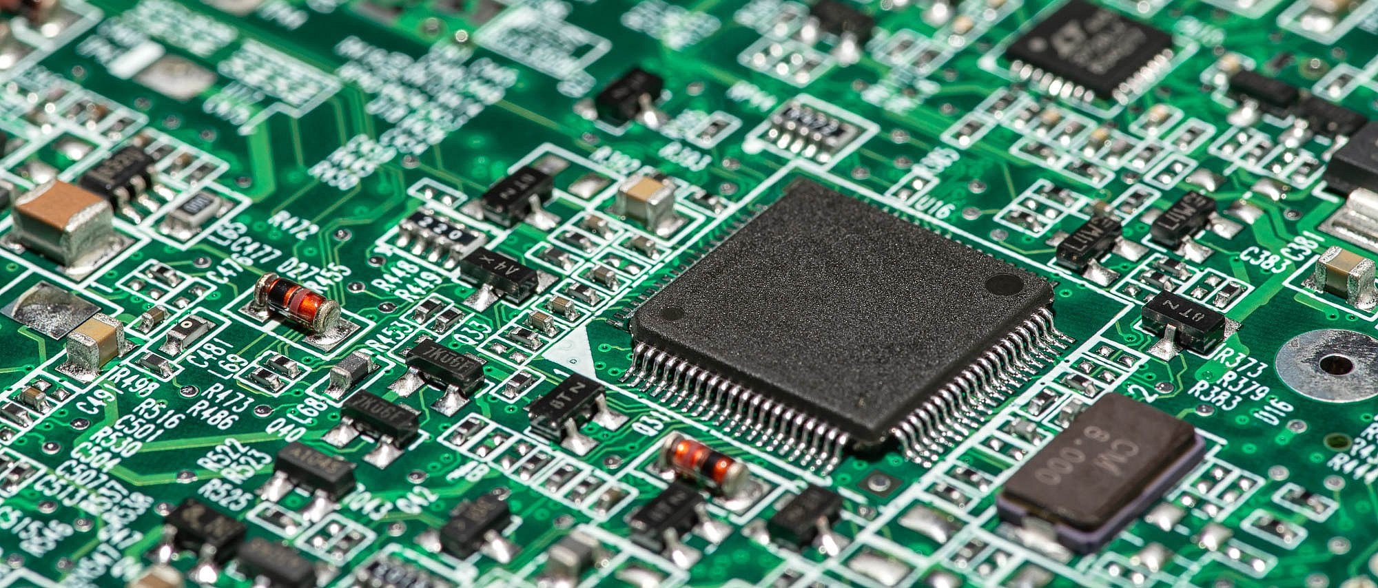 Macro image of a green computer printed circuit board with selective focus on an blank chip